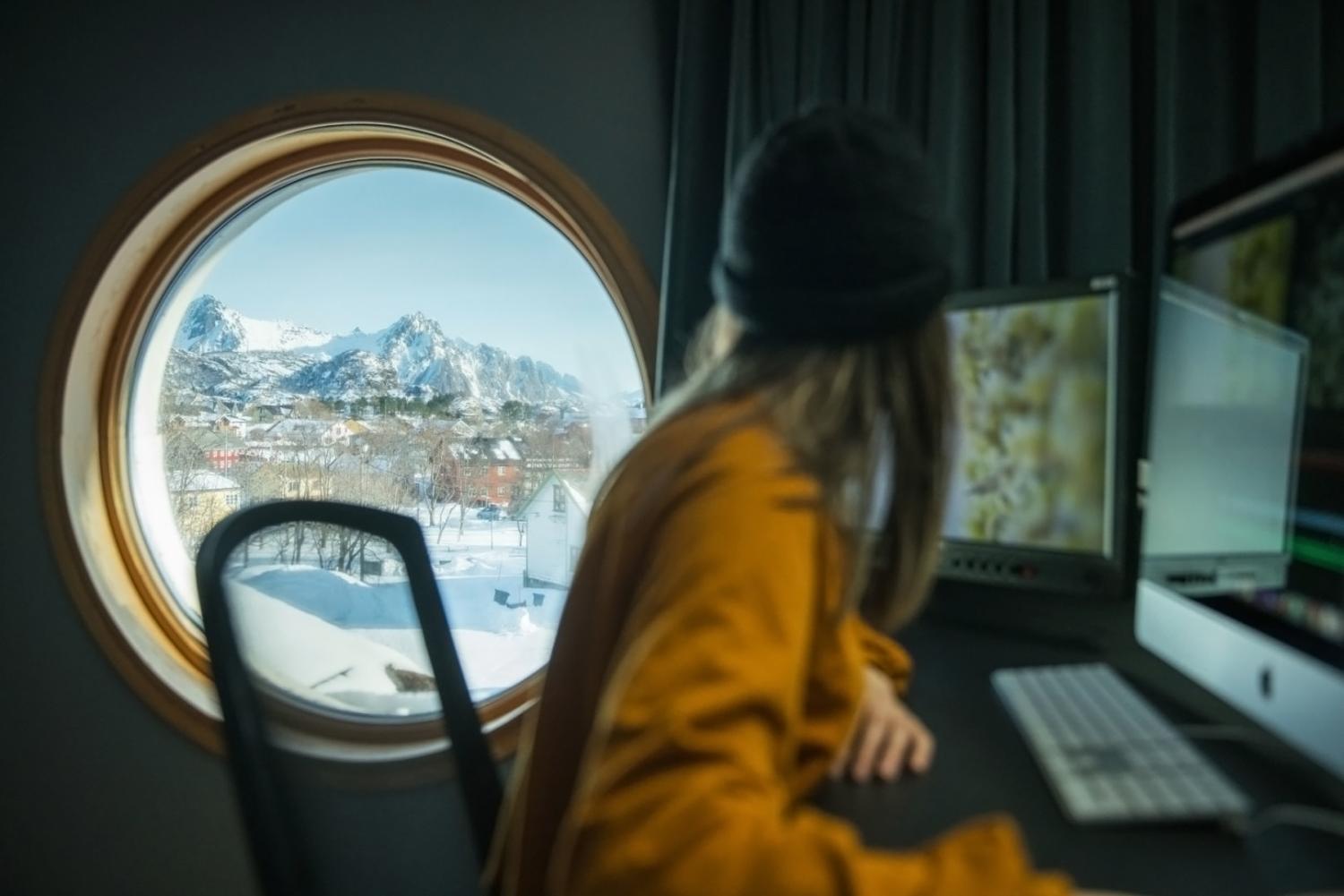 Student som ser ut et vindu i klipperommet ved filmkunstskolen i Kabelvåg.