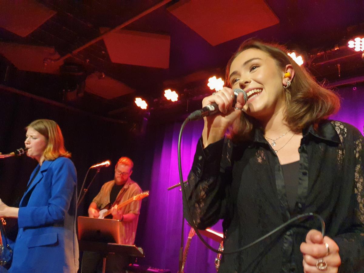 Kvinne synger med band. 