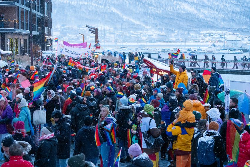 mange personer i pride tog med pride flagg mens det snør 