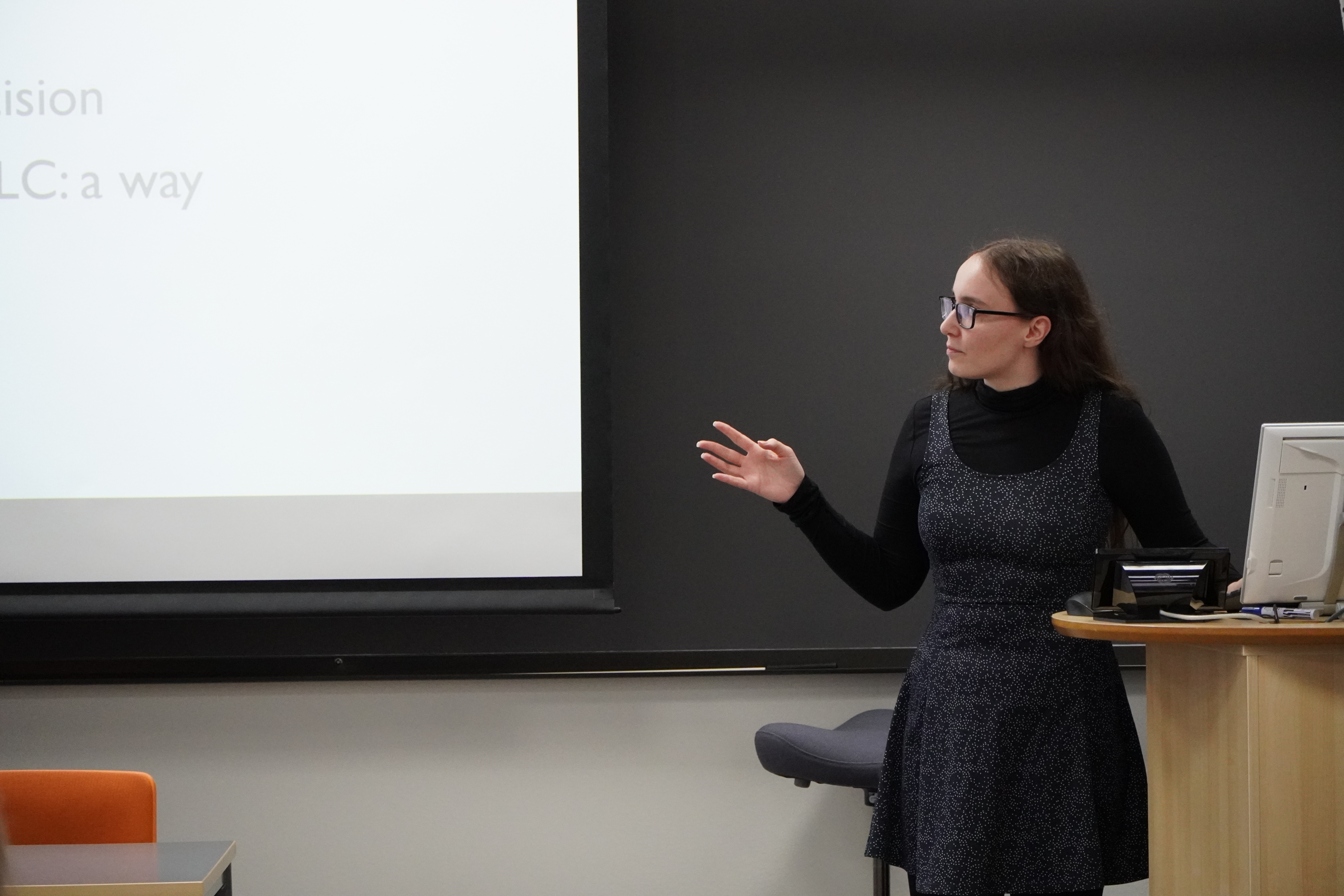 The speaker is pointing to her presentation