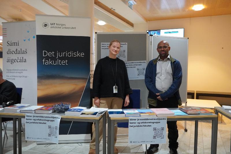 Mann og kvinne foran standen til Det juridiske fakultet