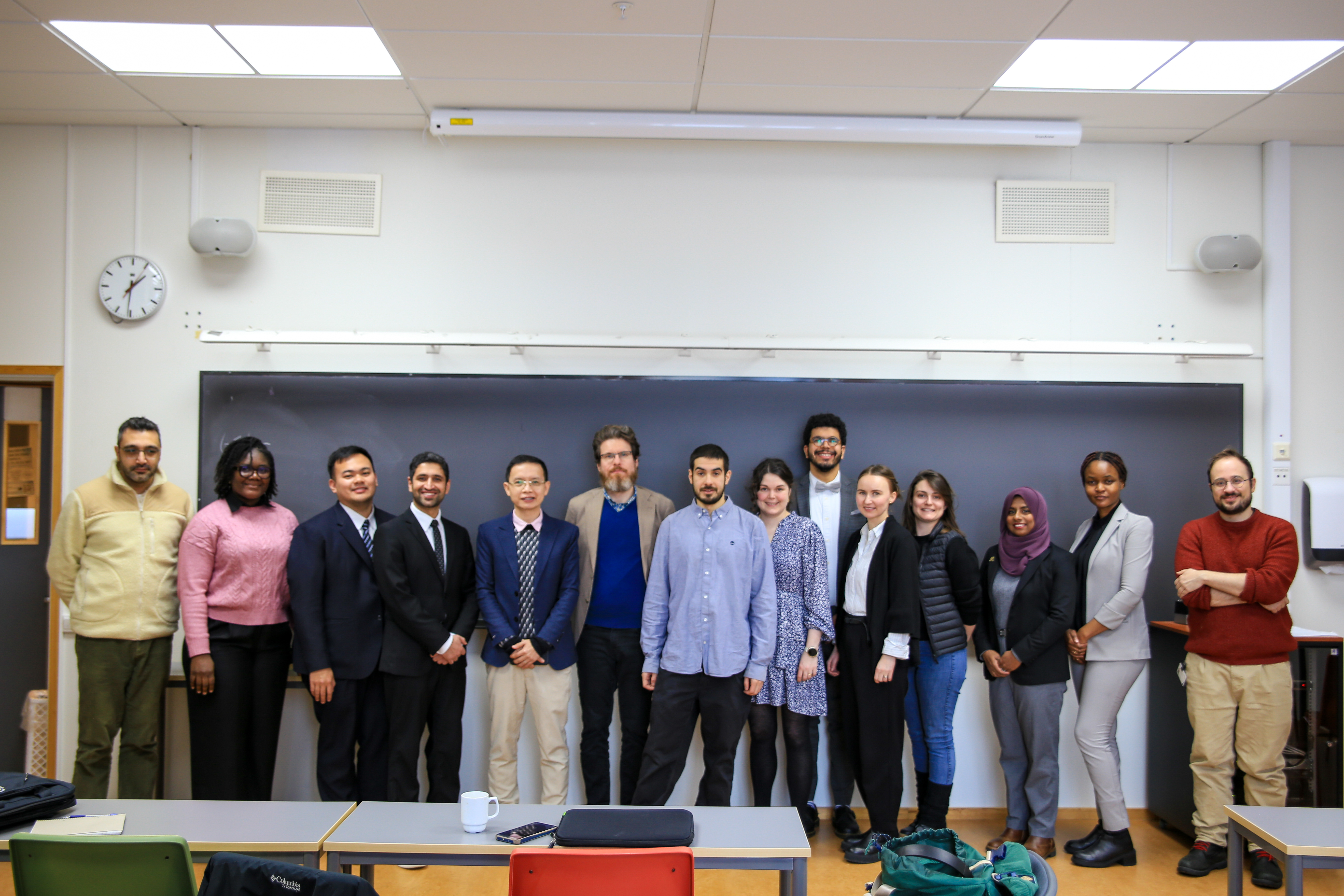 several people standing next to each other in a line posing for the photo, in a classroom